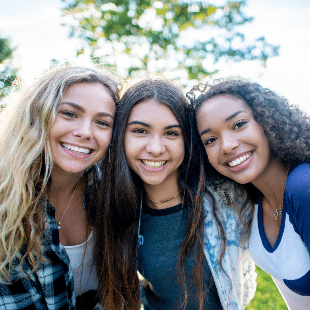 Three college students smiling outdoors in Boulder, Colorado